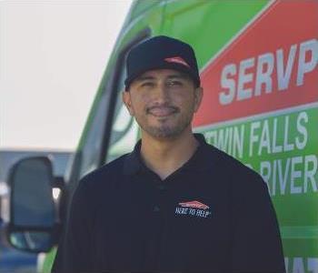 man in black shirt in front of green SERVPRO van